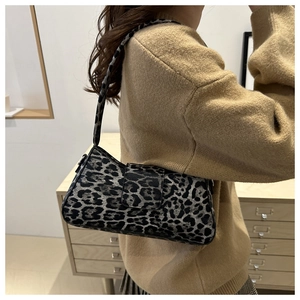 Detailed view of trendy leopard print baguette bag on a model wearing a camel sweater