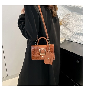 Détail du sac à main marron motif crocodile avec boucle dorée et mini pochette suspendue