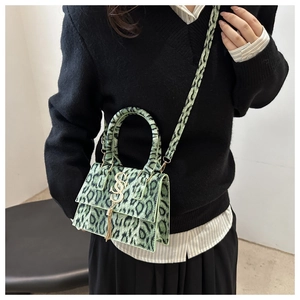 Detailed view of green leopard print crossbody bag with gold S-logo on a model