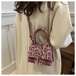 Pink leopard print mini handbag with golden logo tassel on a stylish white coat