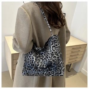 Detail of leopard print tote bag texture and metal buckle on a shoulder strap