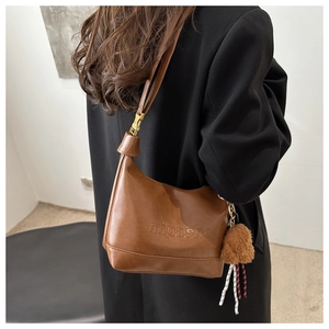 Close-up of brown vintage leather shoulder bag with logo embossing and puppy charm