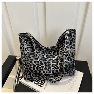 Detail of black and white leopard print tote bag with magnetic closure on a leather chair