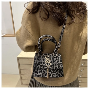 Detailed view of leopard print crossbody bag with SS metal logo and fringe tassel charm