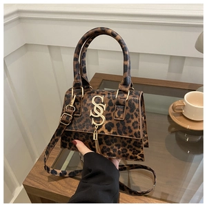 Close-up of stylish leopard print handbag featuring gold logo and metallic tassel detail