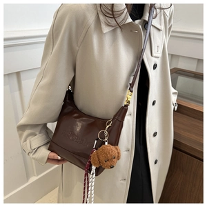 Deep brown leather tote bag with embossed logo and a cute teddy dog plush charm