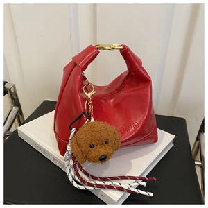 Detail of red leather handbag with gold buckle and brown poodle plush keychain charm