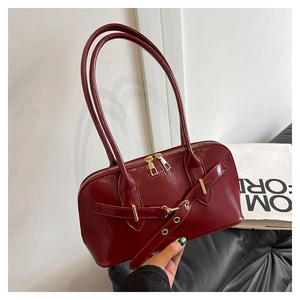Detail of burgundy oil wax leather bag with embossed fashion lettering and gold zipper