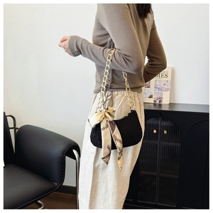 Détail du sac hobo en daim noir avec chaîne dorée et élégant foulard en soie fleurie