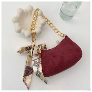 Détail du sac croissant en daim bordeaux avec chaîne dorée et foulard en soie vintage