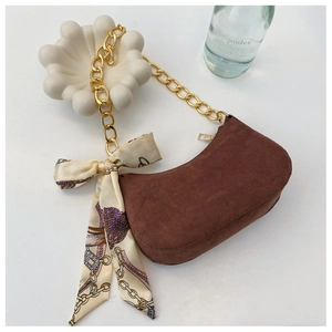 Détail du sac hobo en daim marron avec chaîne dorée et accessoire élégant en foulard