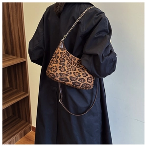 Détail d'un sac hobo léopard porté épaule avec chaîne et bandoulière en cuir