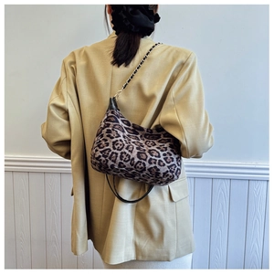 Détail du sac léopard avec bandoulière en chaîne dorée sur un fond minimaliste