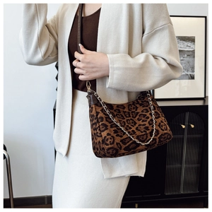 Détail du sac léopard en suédine avec chaîne dorée porté par un mannequin en intérieur