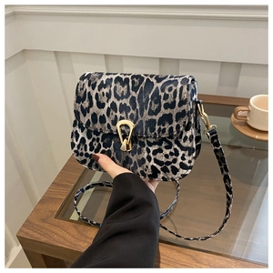 Détail du sac bandoulière léopard avec fermoir fer à cheval doré sur table en bois