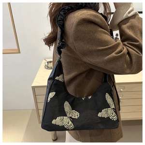 Detail of black hobo bag with golden butterfly embroidery and ruched shoulder strap