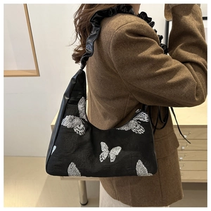 Elegant black crescent hobo bag with silver butterfly embroidery and ruffled strap