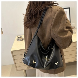 Black leather butterfly hobo bag with gold metal buckle shown in a warm indoor setting