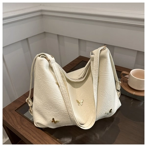Detail of cream tote bag featuring pleated leather texture and gold butterfly ornaments