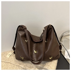Detail of dark brown hobo bag with gold butterfly accents on beige knitted fabric