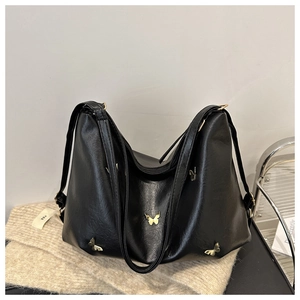 Detailed view of black leather shoulder bag with decorative gold butterfly charms