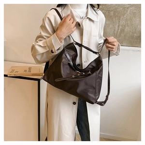 Detail of dark brown nylon tote bag featuring adjustable leather straps and metal eyelets