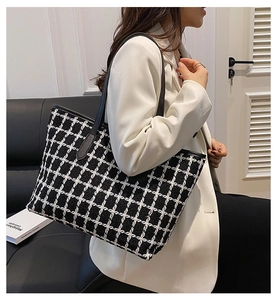 Black and white checkered tweed tote bag shown on model in a modern office interior