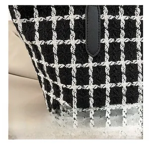 Close-up of black and white plaid tweed fabric texture and black leather handle detail