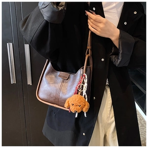 Minimalist brown leather shoulder bag with plush teddy pendant and red dotted scarf detail