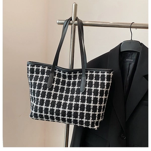 Detail of black and white checkered woven tote bag with premium leather handles