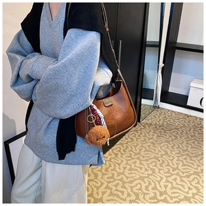 Brown faux leather underarm bag with a plush bear charm and fashion logo detail