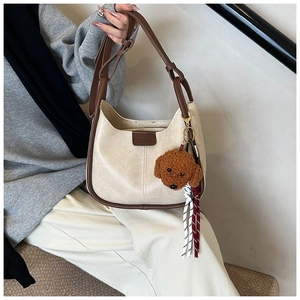 Close-up of cream PU leather shoulder bag with brown trim and cute plush puppy keychain