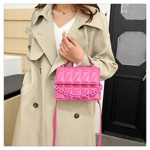 Sac bandoulière matelassé rose avec grosse chaîne et sangle porté par un mannequin