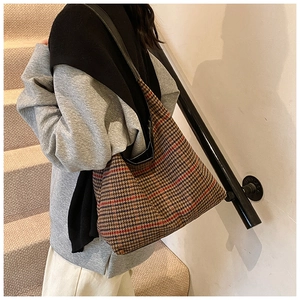 Close-up of houndstooth plaid tote bag with black leather strap on a shoulder