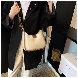 Detail of minimalist cream shoulder bag with brown piping and embossed leather logo