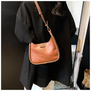 Detail of brown faux leather shoulder bag with FASHION embossing and adjustable strap