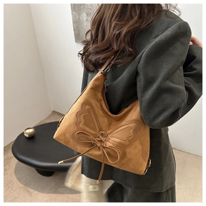 Detailed view of the brown suede shoulder bag featuring a decorative butterfly lace-up design