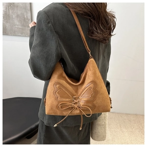 Detail of a brown suede shoulder bag with a vintage butterfly lace-up design for women