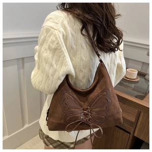 Detail of a brown suede tote bag with leather butterfly patch and lace-up design