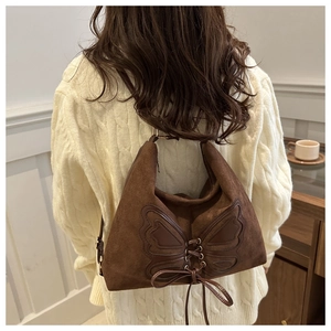 Detail of dark brown suede shoulder bag with a large butterfly applique and leather drawstrings