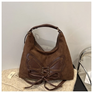 Detail of brown suede hobo bag featuring leather butterfly applique and lace-up accents