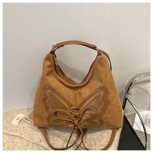 Detailed view of butterfly leather patchwork and lace-up design on brown suede tote bag