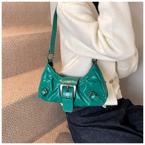 Close-up of a green crescent-shaped leather underarm bag with large metal buckle detail
