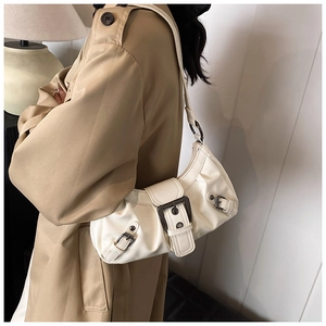 Detail view of cream white faux leather shoulder bag with metallic buckle and belt accents