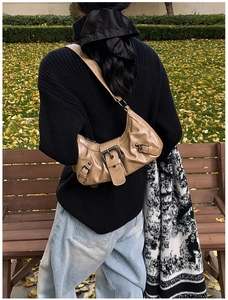 Detail of khaki leather crescent underarm bag with metal buckle and pleated design