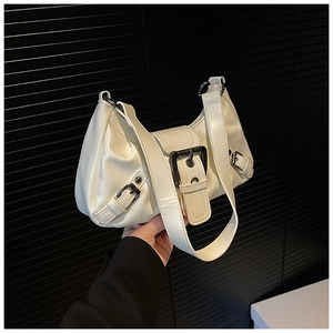 Close-up of white crescent bag with black buckle strap detail and polished faux leather