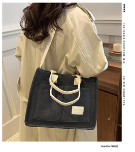 Detail view of large canvas tote bag with dual front pockets and adjustable strap