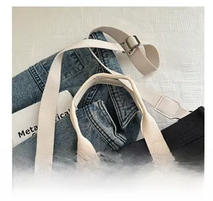 Detail of adjustable cream fabric shoulder strap on a black canvas tote bag