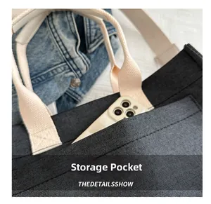 Detail of dark grey canvas tote bag featuring a front storage pocket for a smartphone