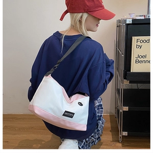 Dettaglio di una grande borsa tote color-block con tracolla nera e logo del marchio